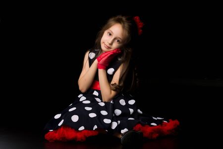 Girl dressed in retro fashion clothes sitting on a black background.の写真素材