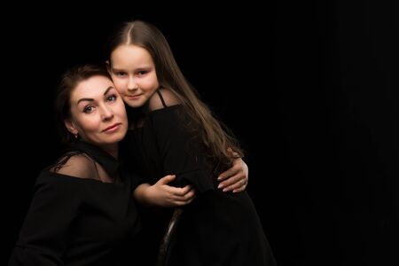 Mom and daughter in the studio on a black background.