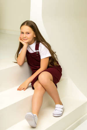 A little girl is standing on a white staircase.の写真素材