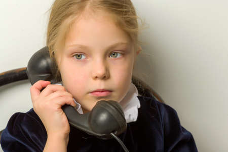 A little girl is ringing on the old phone.の写真素材