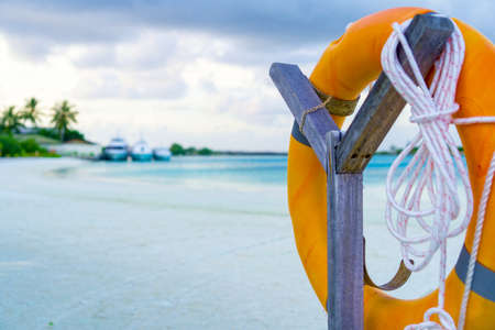 Lifebuoy on Wooden Stand on Blured Background of Blue Water and Yachtsの写真素材