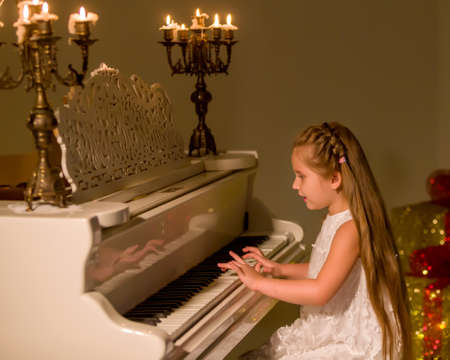 Little girl plays the piano by candlelight.の写真素材