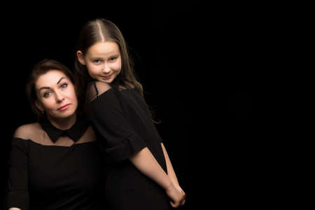 Mom and daughter in the studio on a black background.の写真素材