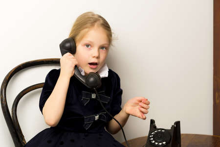 A little girl is ringing on the old phone.の写真素材