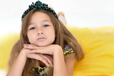 A little girl is lying on the floor. Studio photo session on a white background.の写真素材