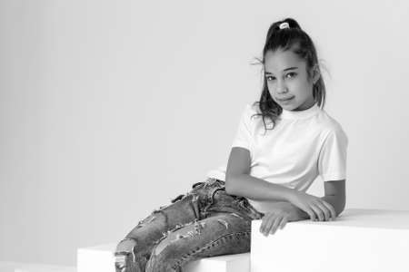 Little girl poses for a magazine in the studio on a white cube.の写真素材