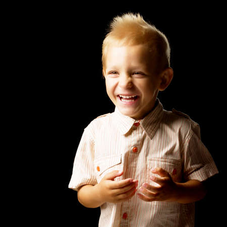 Beautiful little boy on a black background, close-up.