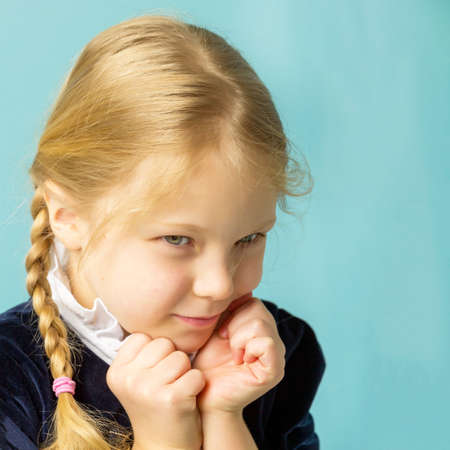 Little girl posing in the studio.She folded her arms near her face, and looks directly at the...