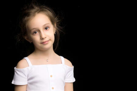 Close up view of a cute smiling little girl posing on black background.の写真素材