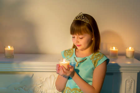 A little girl in a dark room by candlelight.の写真素材