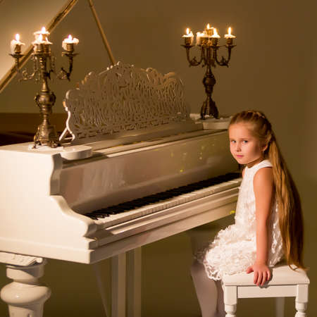 Little girl plays the piano by candlelight.の写真素材