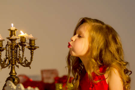 Charming Preteen Girl Blowing out Candles in Vintage Chandelierの写真素材