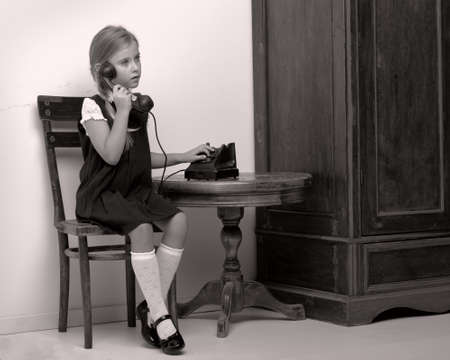 Cute girl speaking via vintage phonの写真素材