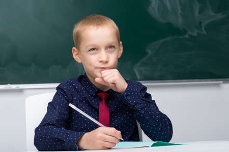 Thinking schoolboy studying at schoolの写真素材