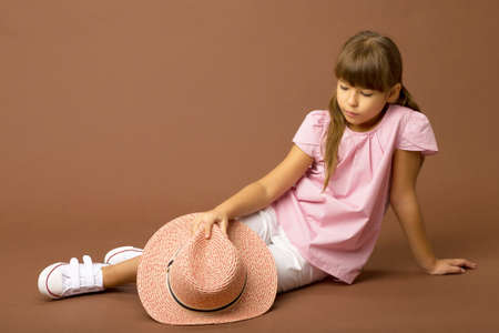Beautiful girl with straw hat sitting on floorの写真素材