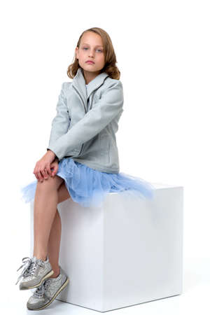 Beautiful girl sitting on white cubeの写真素材