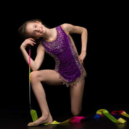 Girl gymnast in the studio on a black background performs gymnastic exercises.の写真素材