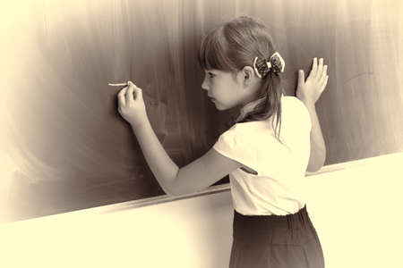 Back view of schoolgirl standing at blackboardの写真素材
