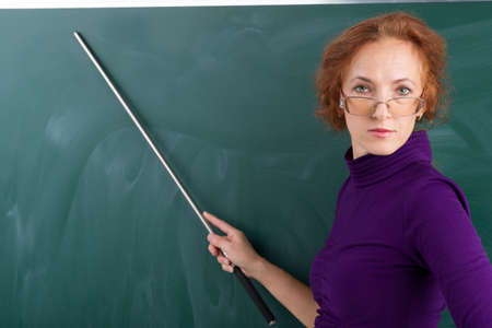 Teacher standing in front of blackboard. Photo session in the studioの写真素材