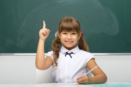 Cheerful schoolgirl pointing up her finger. Photo session in the studioの写真素材