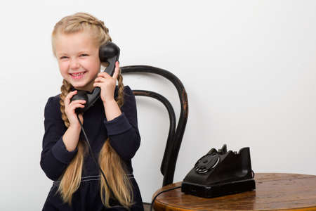 Blonde girl talking by old black phoneの写真素材