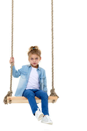 Lovely Blonde Girl Swinging on Rope Swing and Looking at Cameraの写真素材