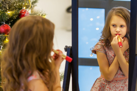 Girl Applying Lipstick in front of Mirror Looking at her Reflectの写真素材