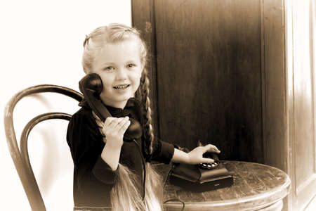 Smiling girl talking by old phoneの写真素材
