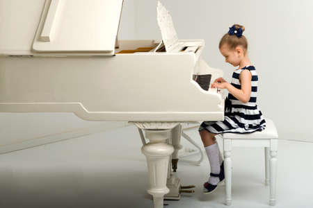 Side view of cute little girl playing grand pianoの写真素材