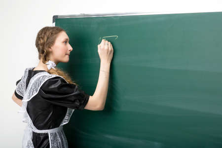 Focused girl writing with chalk on the blackboardの写真素材