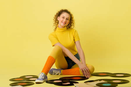 Happy girl sitting on floor with vinyl records