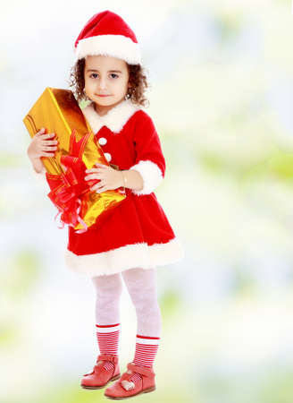 Little girl in costume of Santa Claus with giftの写真素材