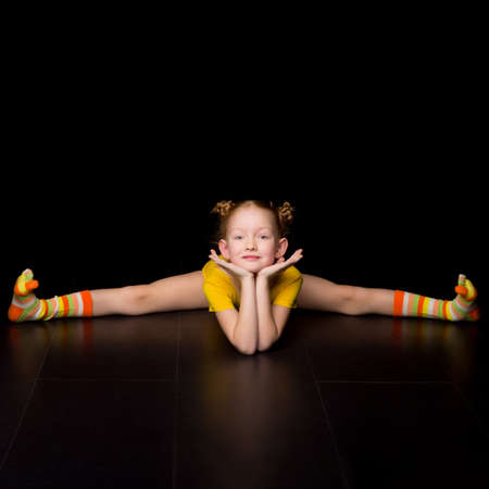 Cute happy young girl gymnast doing cross splitsの写真素材