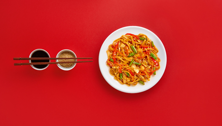 Fried noodles with vegetables. Asian vegetarian food on red backgroundの写真素材