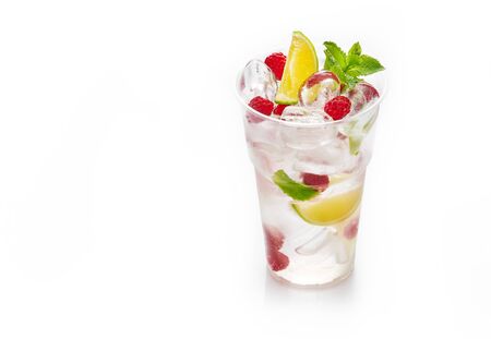 Fresh cold lemonade with soda, ice cubes, mint, lime and raspberry on white backgroundの写真素材