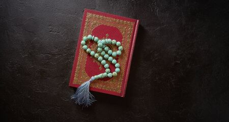Islamic holy book quran and rosary beads on black stone or slate texture background. Islamic concept with copy space, top viewの写真素材