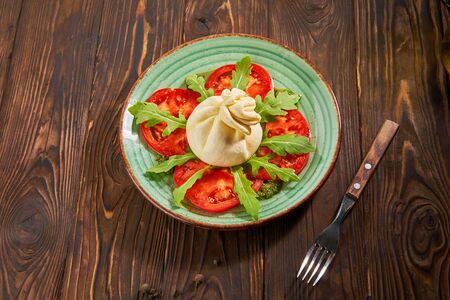 Italian caprese salad with tomatoes and cheese on wooden tableの写真素材