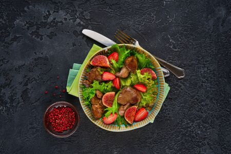 Green salad with liver and strawberry on dark rustic backgroundの写真素材