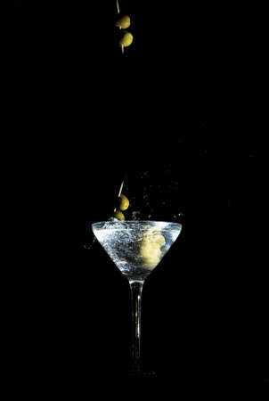 Two calamata olives on a toothpick dropped into a martini glassの写真素材