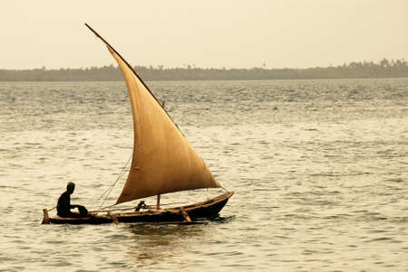 Fisherman going out to sea at dusk on Zanzibar Island off the coast of Tanzania, Africaの写真素材