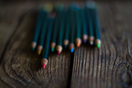 Coloured pencils lined up on wooden tableの写真素材