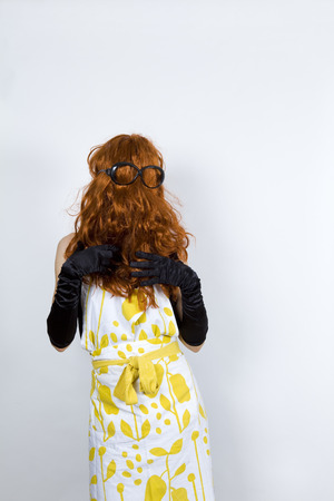 anonymous faceless housewife wearing an apron over an evening dress and evening gloveswig upside down, front faceglasses on the wigの写真素材