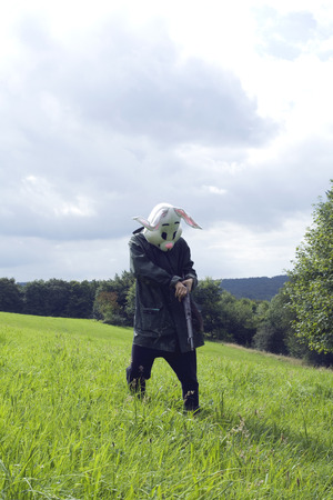 woman wearing a rabbit mask hunting with shotgun in a forestの写真素材