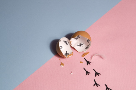 The counting of the days on a broken egg with footprint on a pink and blue backgroundの写真素材