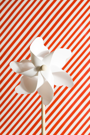 A white pinwheel on a Striped red and white backgroundの写真素材