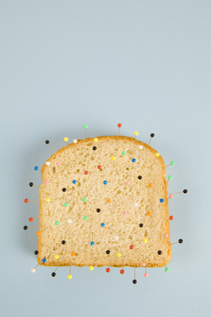 still life photography of a quirky soft bread stacked and used as a voodoo doll on a blue and minimal backgroundの写真素材