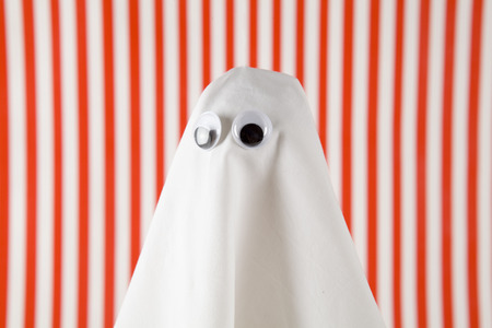 white sheet ghost with doll's eyes isolated on a striped background. white and red backgroundの写真素材