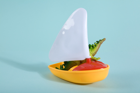 A dinosaur lost at sea on a toy boat like a noah's ark metaphor. Minimal Poetic still life photographyの写真素材