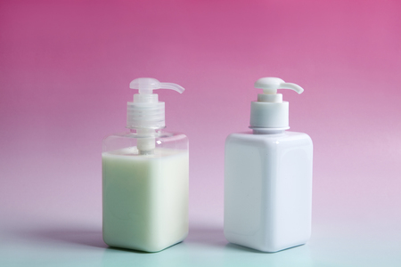 two rectangular pump bottles : white and transparent,  on a gradient blue and pink vibrant background. harmony of colors. Minimal color still life photographyの写真素材