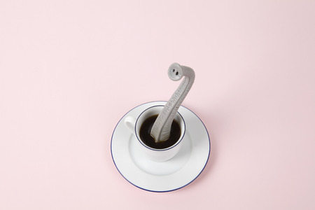 An elephant trunk emerging from a small design cup of coffee as if he were hiding. Minimal funny and quirky design still life photographyの写真素材